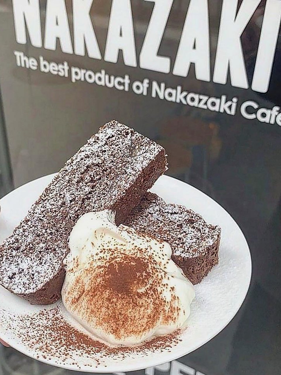 ココアをふったクリームを添えたチョコレートのケーキ